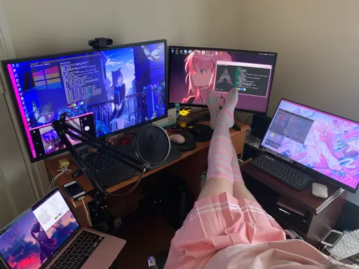 photo of a person resting their legs on their desk pc setup, wearing pink striped thigh highs, a pink skirt and pink t-shirt and collar. four computers can be seen. from left to right, a macbook air m1, a desktop pc running windows 10 connected to a 32 inch 4K monitor, a desktop pc running arch linux connected to a 27 inch curved 180hz 1440p monitor, and a gaming laptop running windows 10, connected to a 22 inch touch-screen 1080p monitor.